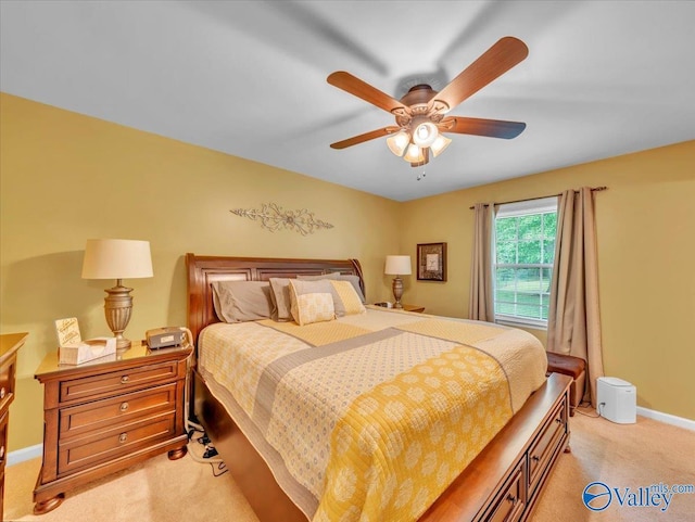 bedroom featuring light colored carpet, a ceiling fan, and baseboards