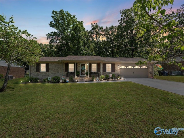 ranch-style home featuring concrete driveway, a garage, and a lawn