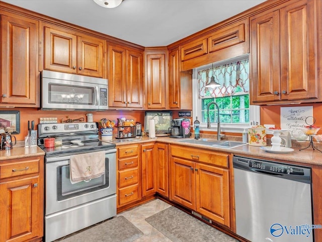 kitchen with stainless steel appliances, a sink, and brown cabinetry
