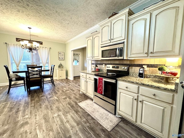 kitchen with pendant lighting, dark wood-type flooring, stainless steel appliances, cream cabinets, and ornamental molding