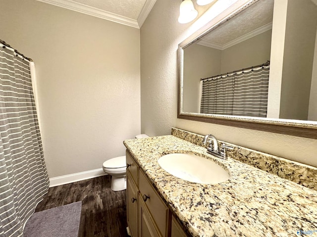 bathroom with wood-type flooring, ornamental molding, vanity, toilet, and a textured ceiling