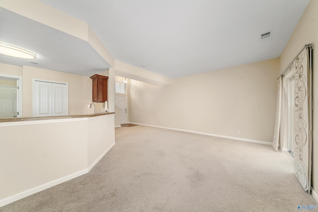 unfurnished living room with light carpet and sink