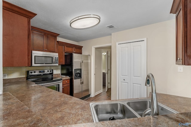 kitchen with tasteful backsplash, a textured ceiling, dark wood-type flooring, sink, and stainless steel appliances