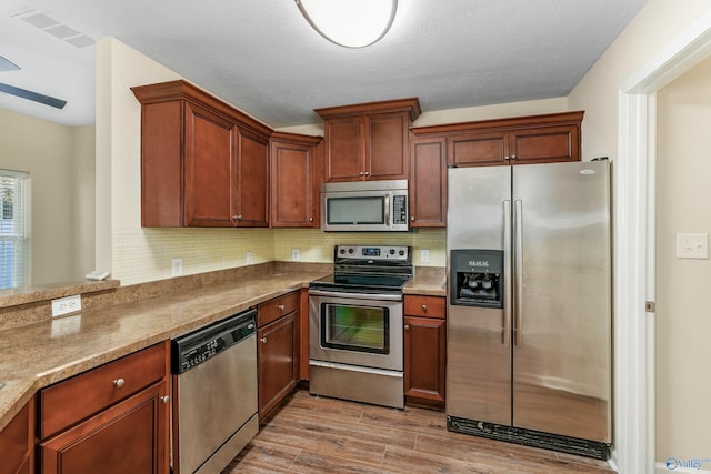 kitchen with tasteful backsplash, appliances with stainless steel finishes, a textured ceiling, and light wood-type flooring