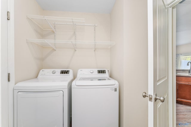 laundry area featuring sink, washer and clothes dryer, and hardwood / wood-style flooring