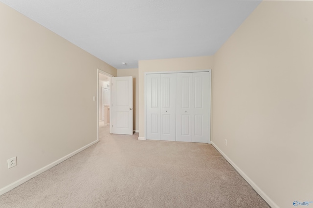 unfurnished bedroom with a closet and light colored carpet