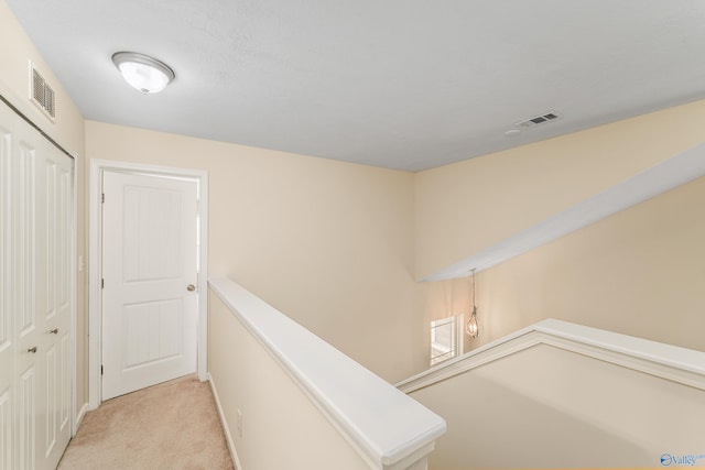 hall with a textured ceiling and light colored carpet