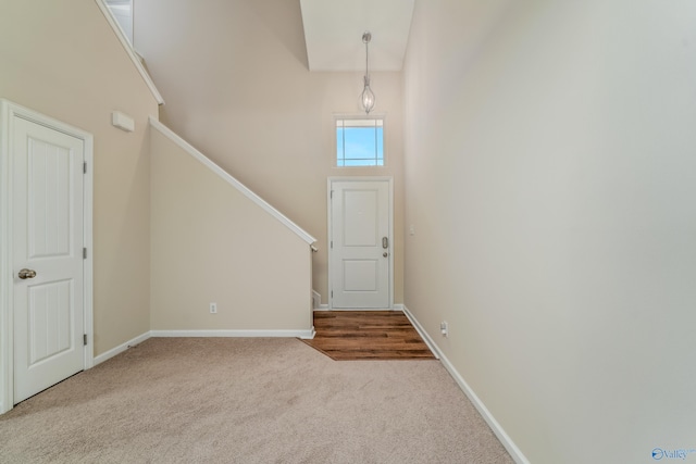 foyer with light colored carpet and high vaulted ceiling