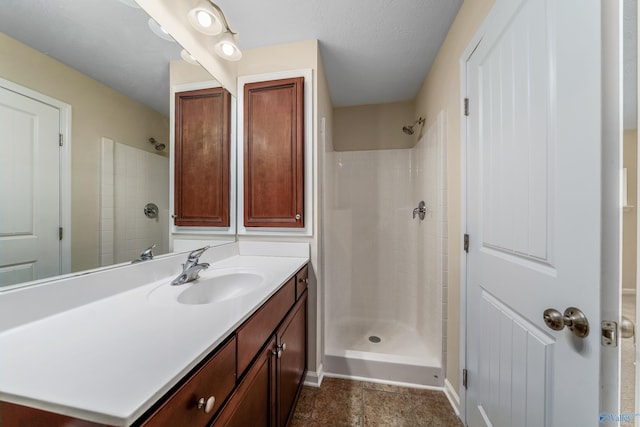 bathroom with vanity, a shower, and a textured ceiling