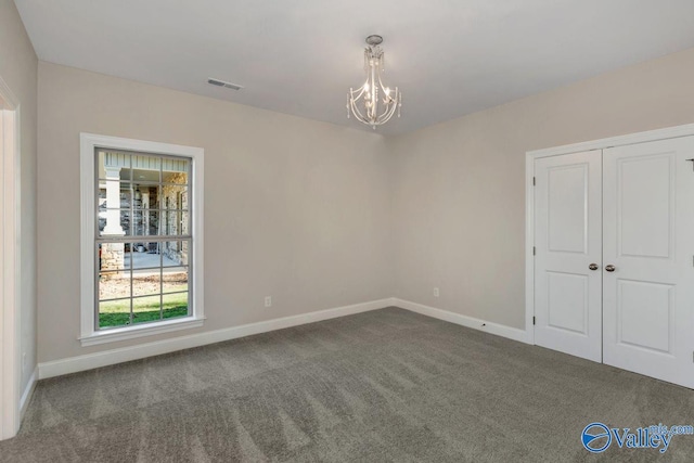 carpeted empty room with an inviting chandelier