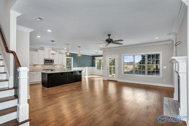 unfurnished living room with dark wood-type flooring, ceiling fan, sink, and crown molding