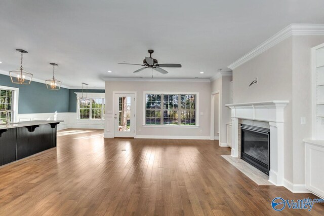 unfurnished living room with ceiling fan, wood-type flooring, and crown molding