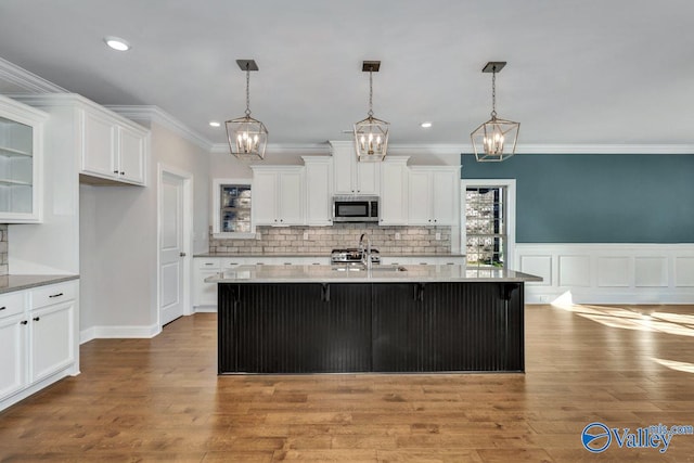 kitchen featuring pendant lighting, hardwood / wood-style flooring, a center island with sink, and stainless steel appliances