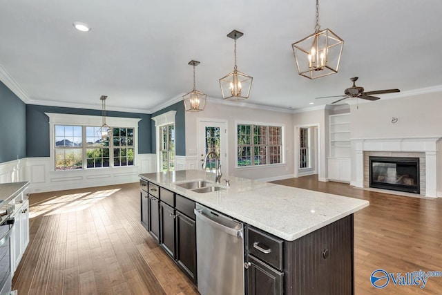 kitchen with a center island with sink, light wood-type flooring, appliances with stainless steel finishes, pendant lighting, and sink