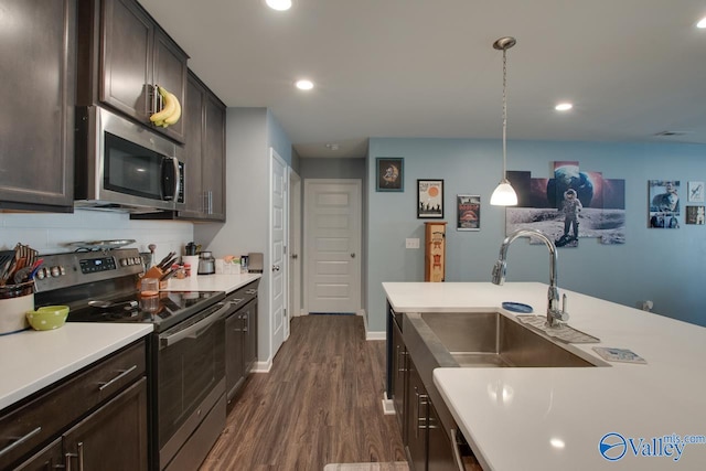 kitchen featuring sink, decorative backsplash, appliances with stainless steel finishes, pendant lighting, and dark hardwood / wood-style flooring