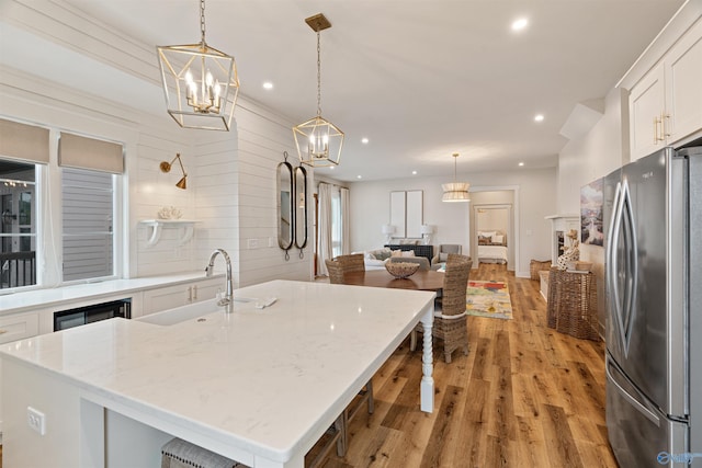 kitchen with light wood-type flooring, a sink, white cabinetry, recessed lighting, and freestanding refrigerator
