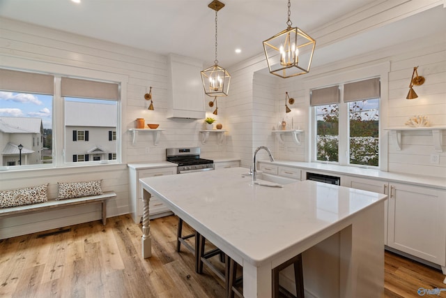 kitchen featuring open shelves, custom range hood, stainless steel gas range oven, and a sink