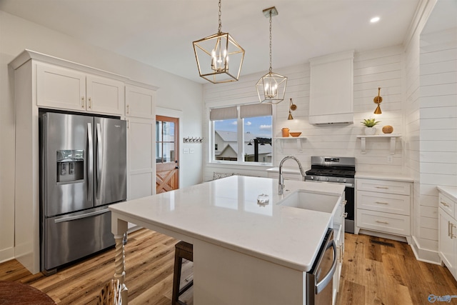 kitchen with premium range hood, light wood finished floors, a sink, white cabinets, and appliances with stainless steel finishes