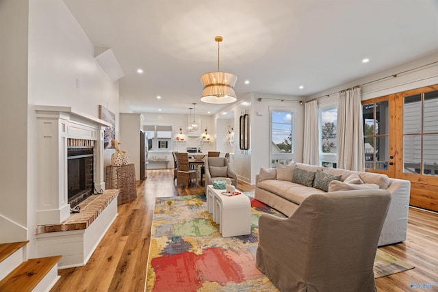 living area with recessed lighting, light wood-style floors, and a brick fireplace
