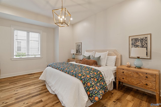 bedroom featuring baseboards, a notable chandelier, and wood finished floors