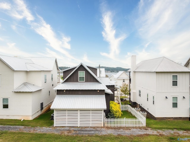 back of property featuring metal roof, board and batten siding, and fence