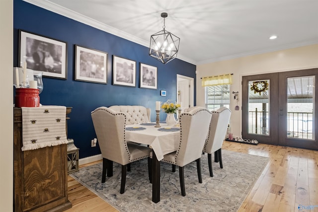 dining area with a chandelier, crown molding, french doors, and light hardwood / wood-style floors