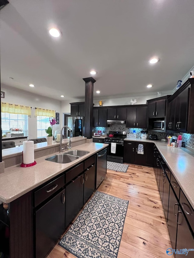 kitchen featuring backsplash, sink, an island with sink, appliances with stainless steel finishes, and light hardwood / wood-style floors