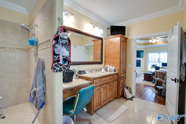 bathroom with vanity, hardwood / wood-style floors, a tile shower, and crown molding