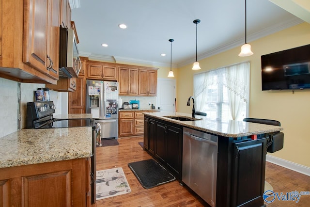 kitchen with sink, a kitchen island with sink, stainless steel appliances, and wood-type flooring