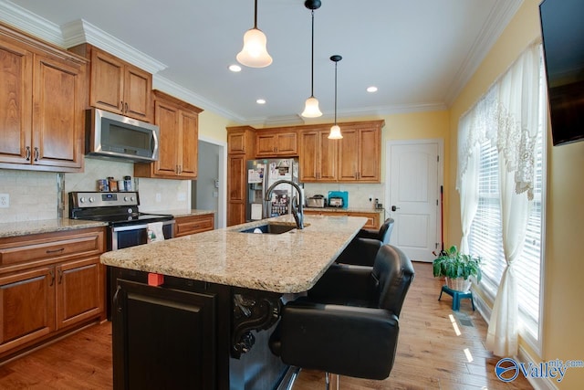 kitchen featuring appliances with stainless steel finishes, sink, a kitchen breakfast bar, light hardwood / wood-style flooring, and a center island with sink