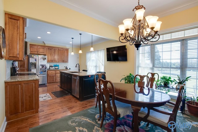 dining area with sink, dark wood-type flooring, crown molding, and a chandelier