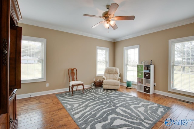 living area with ceiling fan, ornamental molding, and light hardwood / wood-style flooring