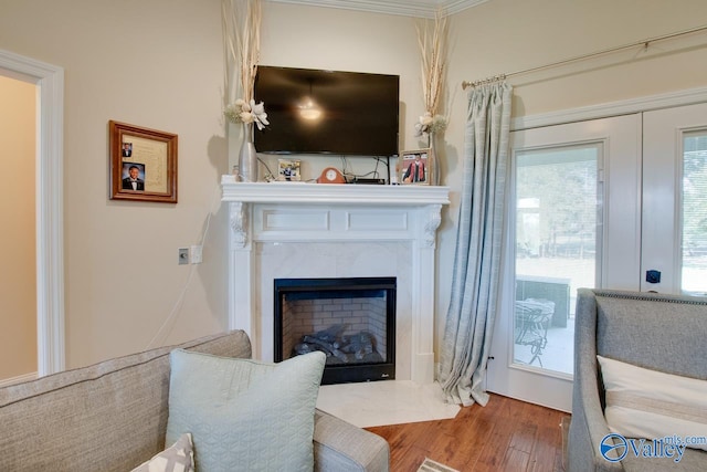 living area with ornamental molding, hardwood / wood-style floors, and a fireplace