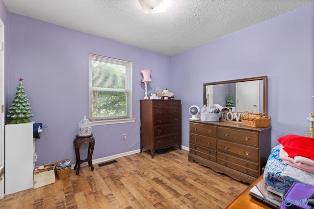 bedroom featuring a textured ceiling and light hardwood / wood-style flooring