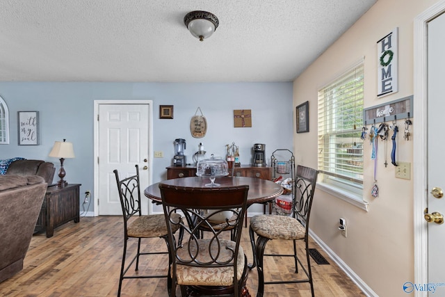 dining room featuring a textured ceiling and light hardwood / wood-style flooring