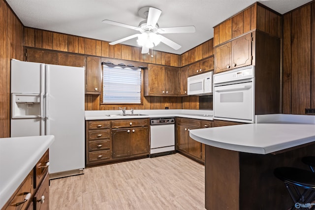 kitchen with sink, white appliances, light hardwood / wood-style flooring, ceiling fan, and kitchen peninsula