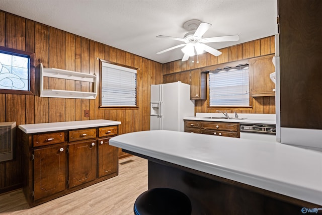 kitchen with white appliances, wooden walls, light hardwood / wood-style floors, and sink