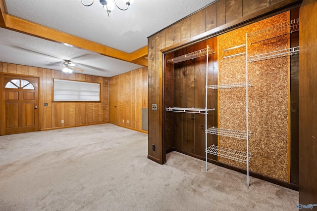 interior space featuring ceiling fan, a textured ceiling, and wooden walls