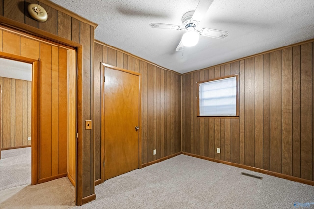 unfurnished bedroom featuring light carpet, a textured ceiling, and ceiling fan