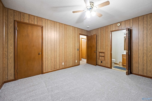 unfurnished bedroom featuring connected bathroom, light colored carpet, ceiling fan, a textured ceiling, and a closet