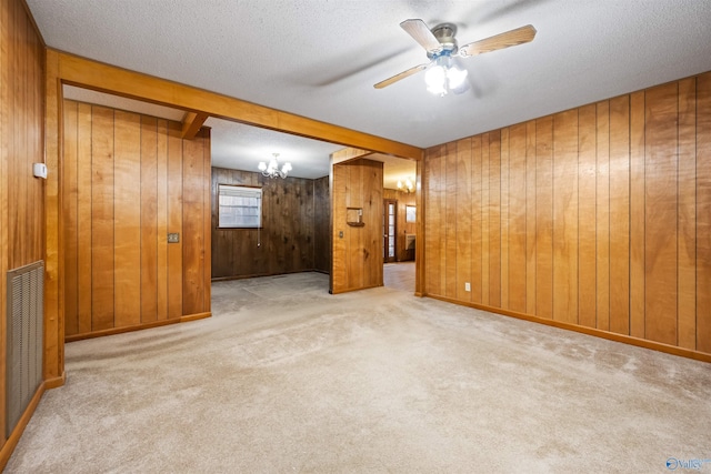 empty room with ceiling fan, a textured ceiling, light carpet, and wood walls