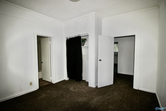 unfurnished bedroom with a closet and dark carpet