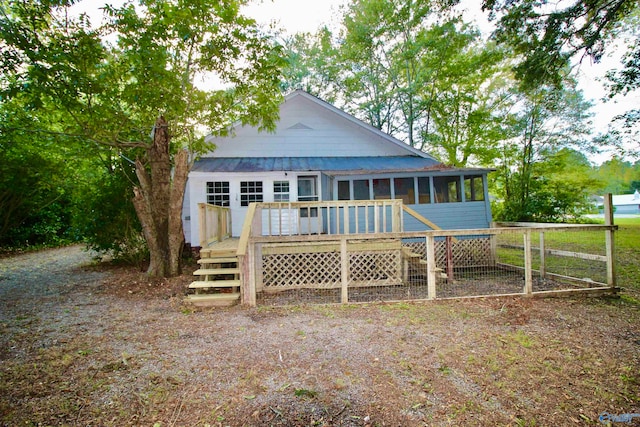 rear view of house featuring a sunroom and a deck