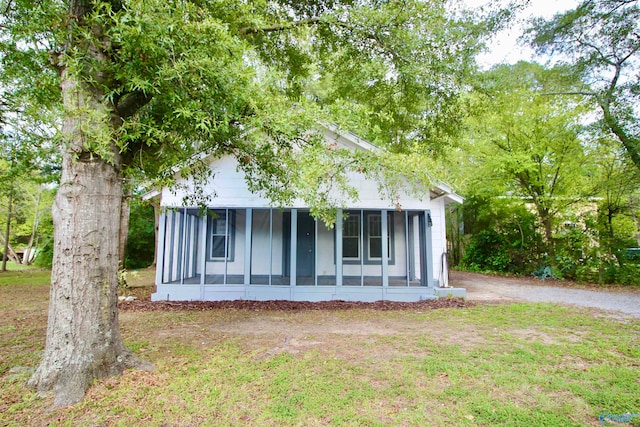 view of side of property with a sunroom and a lawn