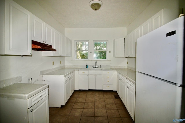 kitchen featuring white cabinetry, a textured ceiling, tile counters, and white fridge