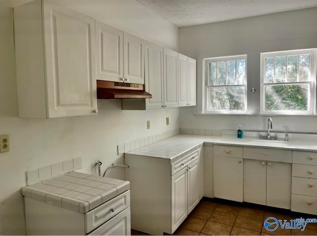 kitchen featuring white cabinets, tile counters, a textured ceiling, and sink