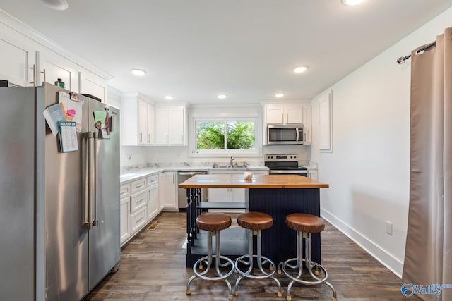 kitchen with white cabinets, a kitchen island, dark hardwood / wood-style floors, and stainless steel appliances