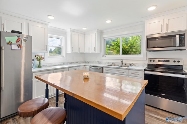 kitchen featuring light wood-type flooring, sink, appliances with stainless steel finishes, and a kitchen island