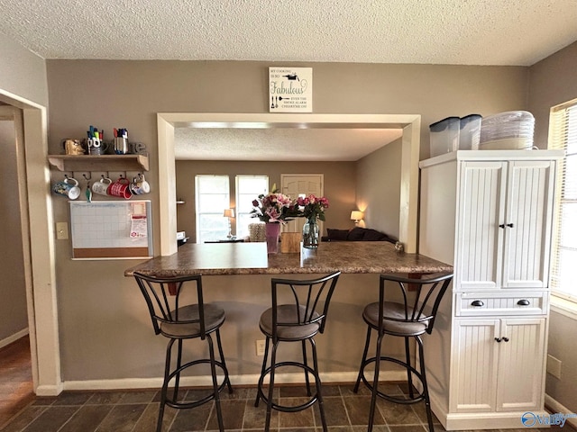 1300 7th Ave, Athens, AL 35611 - kitchen featuring a textured ceiling, a kitchen breakfast bar, plenty of natural light, and dark countertops