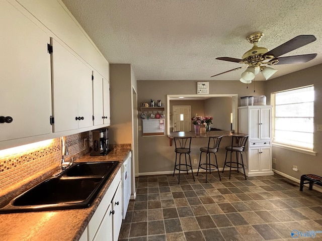1300 7th Ave, Athens, AL 35611 - kitchen with decorative backsplash, white cabinetry, a ceiling fan, baseboards, and a sink